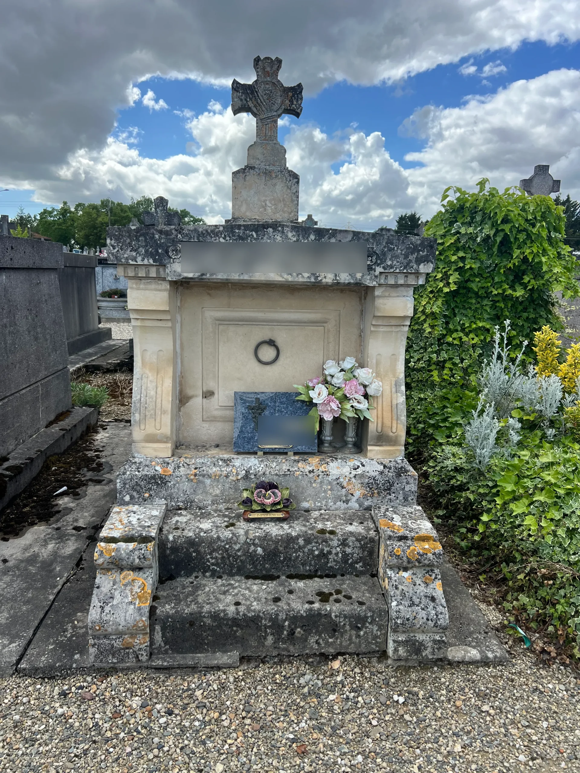 Tombe ancienne en pierre avec grande croix et fleurs entretenue par marbrerie-pompes-funebres-mauvezin à Mauvezin