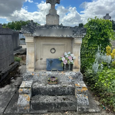 Tombe ancienne en pierre avec grande croix et fleurs entretenue par marbrerie-pompes-funebres-mauvezin à Mauvezin