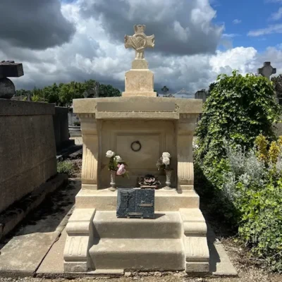 Tombe en pierre claire avec croix et fleurs artificielles chez marbrerie-pompes-funebres-mauvezin à Mauvezin
