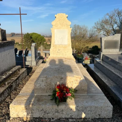 Tombe en pierre claire avec fleurs rouges au cimetière, marbrerie-pompes-funebres-mauvezin à Mauvezin